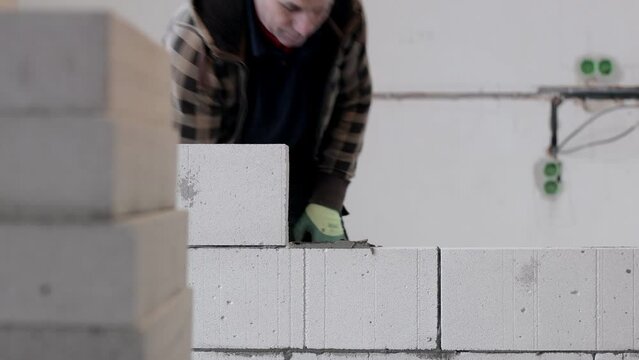 The builder places the block during the construction of the wall.