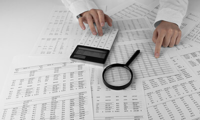 Accountant holding a calculator pointing at numbers on financial documents. Сoncept of finance,...