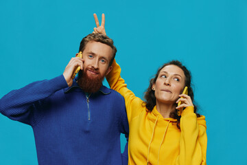 Woman and man cheerful couple with phones in their hands crooked smile cheerful, on blue...