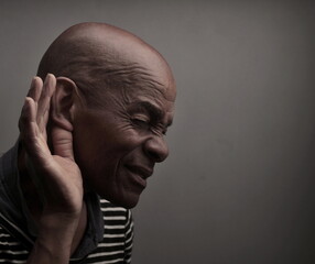 man suffering from deafness and hearing loss on grey background with people stock photo