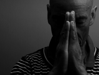 man praying to god with hands together Caribbean man praying on black background with people stock...