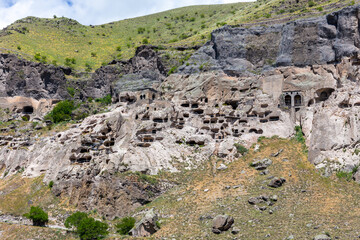 Vardzia cave monastery complex in Georgia landscape, mountain slope with caves, tunnels and dwellings carved in the rock.