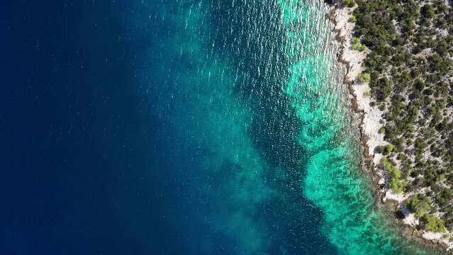 Flying over the turquoise Adriatic Sea waves drone video with lonely yacht near the rocky coast. Aerial coastal top view 4K footage.