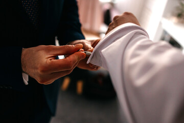 Man's style. dressing suit shirt and cuffs, closeup of hands helping to put the cufflinks on.