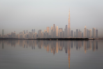 Naklejka premium Dubai Downtown skyline landscape with the skyscrapers reflecting golden sun and reflections in Dubai Creek, sunrise.