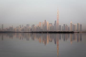 Dubai Downtown skyline landscape with the skyscrapers reflecting golden sun and reflections in Dubai Creek, sunrise.