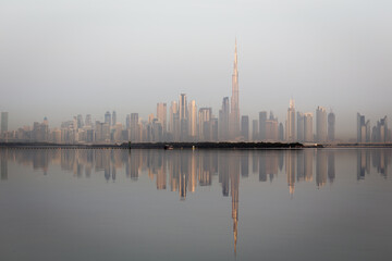 Naklejka premium Dubai Downtown skyline landscape with the skyscrapers reflecting golden sun and reflections in Dubai Creek, sunrise.