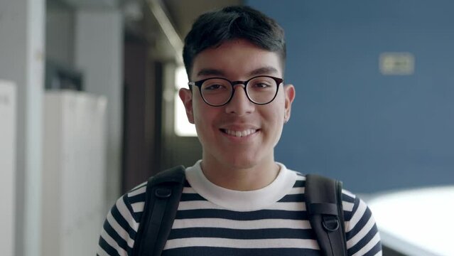 Portrait of smiling hispanic latin college student carrying his backpack standing inside university corridor. Peruvian young male portrait.