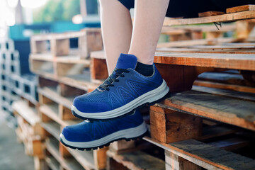 Photo of a woman sitting on old wood and wearing blue sports shoes, these shoes are often called...