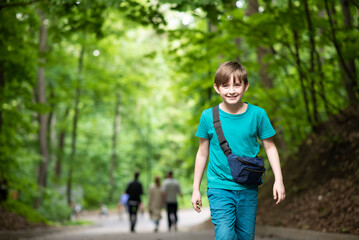 smiling boy walking along the road through the green park