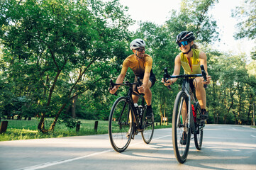 Couple riding bicycles outside of the city and wearing helmets and sunglasses - Powered by Adobe