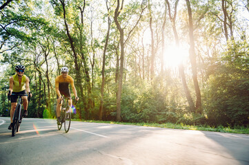 Naklejka premium Couple riding bicycles outside of the city and wearing helmets and sunglasses