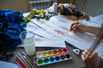 Faceless woman sketches swimwear and underwear. Close-up of fashion designer's hands.