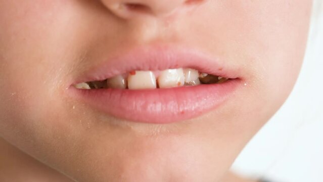 A close-up view of a child happily eating a donut. A child eats a doughnut. Fast food and unhealthy food. 4K resolution video