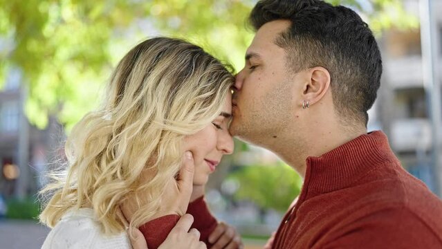 Man and woman couple smiling confident kissing on head at park