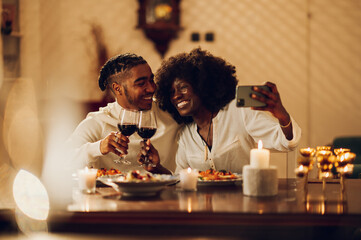 African american couple having romantic date at home and taking selfie with a smartphone