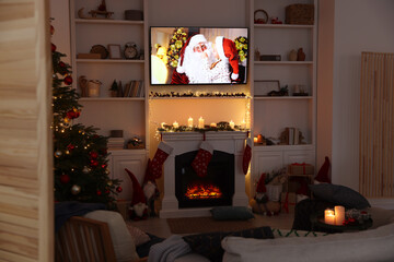 TV set with Christmas movie above fireplace in cosy room. Winter holidays atmosphere