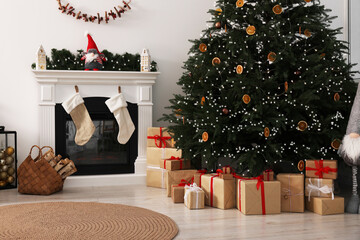 Many different gift boxes under Christmas tree and festive decor in living room