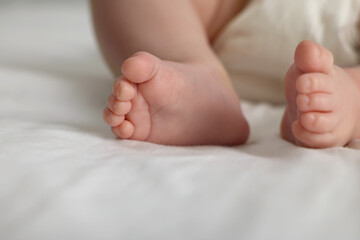 Cute little baby in diaper on bed, closeup