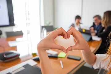 Woman makes a heart with her hands in the office, love for the workplace concept