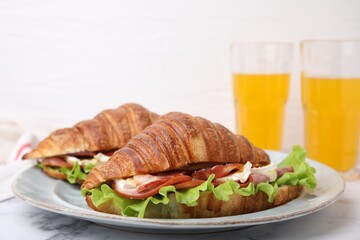 Tasty croissants with brie cheese, ham and bacon on white marble table, closeup