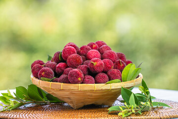 Arbutus berries Fruit or Red Yangmei in basket over blur greenery background, Red Bayberry,...