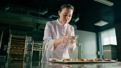 attractive baker sprinkles powdered sugar on ready freshly baked hot fragrant buns baking production bakery
