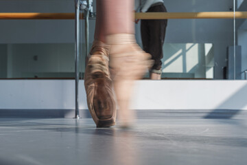 Fototapeta na wymiar female ballet dancer feet in pointe shoes turning with motion blur in choreography studio
