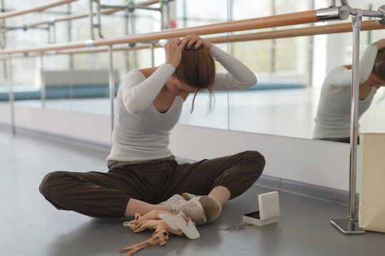 young professional ballerina preparing her hair for rehearsal in choreography class