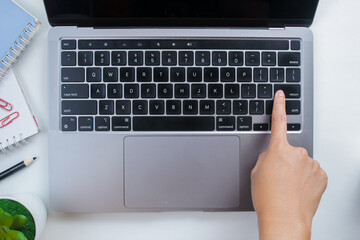 Female finger pressing enter key on computer keyboard. Top view