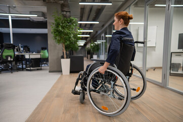 Fototapeta na wymiar Caucasian woman wheelchair in open space office.