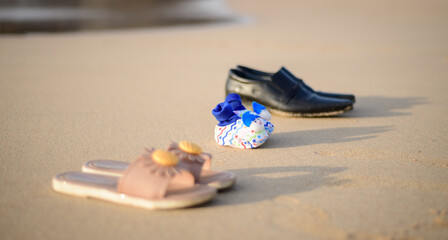 Fototapeta na wymiar Concept of expectant parents, baby shoes and parent's shoes on the beach sand.