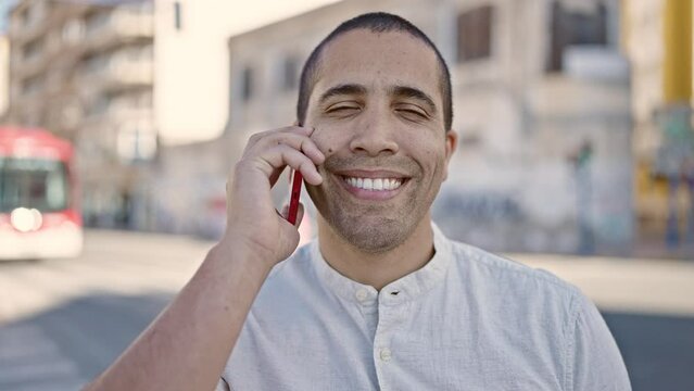 Young hispanic man speaking on the phone at street