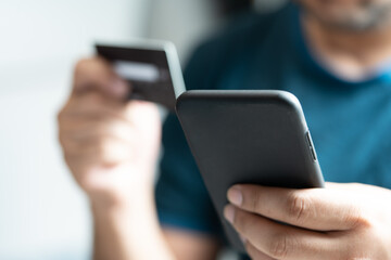 Online payment man hand holding a credit card and using a smartphone for online shopping.