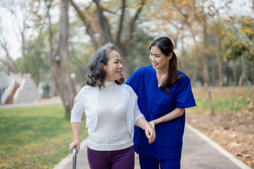 Patient care, female care, young Asian women are taking care of the elderly, providing crutches and walking for patients, and exercising their legs and knees in the park parks.