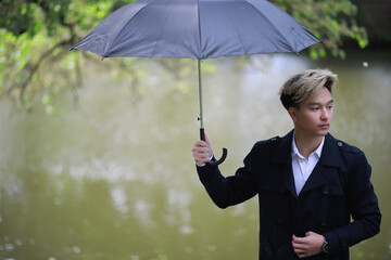 Spring rainy weather and a young man with an umbrella