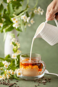 Composition with cup of jasmine milk tea and flowers on green background