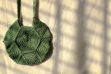 handmade olive green yarn crochet hexagon shape creative bag on white background with sunlight....