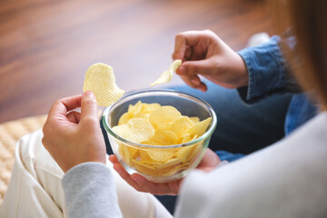 Closeup image of friends sharing and eating potato chips together