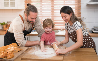 Beautiful cute family having fun while cooking together in the kitchen at home. Family with child in kitchen having breakfast
