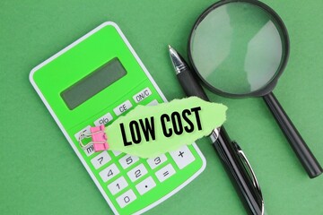 calculator, pen and magnifying glass with words low cost. Business and economic concepts.