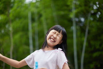 夏の公園でシャボン玉を遊ぶ可愛い小学生の女の子の様子