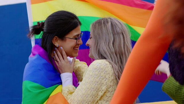 Lesbian couple kissing on LGBTQ parade festival. Two young girlfriends in love. Diverse people of gay and lesbian community celebrating together lgbt pride day month outside. Human rights and freedom