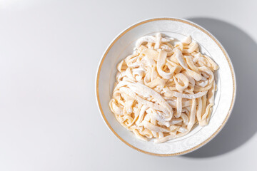 Homemade noodle for lagman in white bowl on grey background, isolated, top view	
