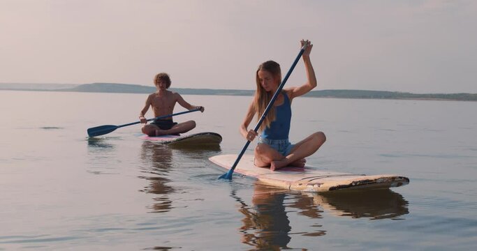 On summer holiday love young couple relax sail sup board surf on river on beautiful nature Slow motion ecotourists on a walk on the lake
