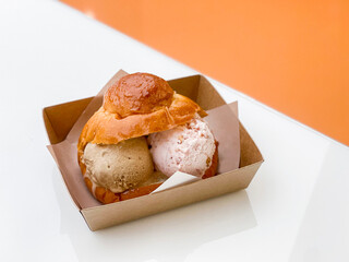 Ice cream with bread. A soft bread stuffed with two scoop of coffee and strawberry cheesecake ice cream.