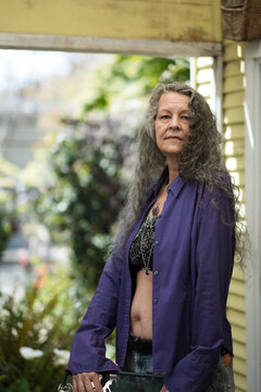 Long silver hair, bare midriff, and face piercings: a queer senior inspires in a backyard portrait.
