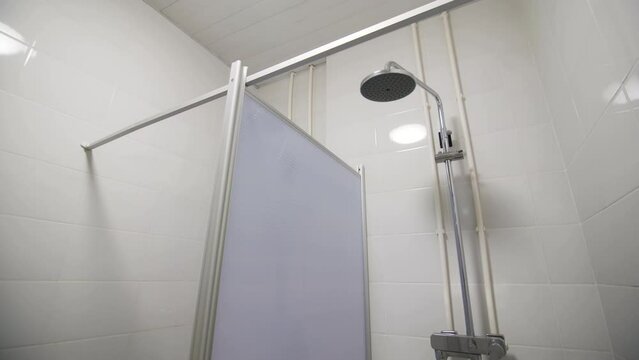 Public shower with plumbing equipment in separated cabins. Hygiene facilities in sports club. Modern washroom with simple interior