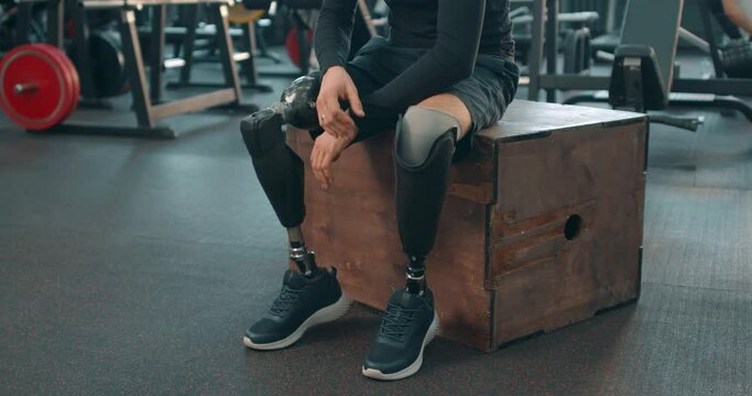 tired sweaty desabled man with artifical bionic legs having reat after workout at gym, Slow motion sportsman has break after training