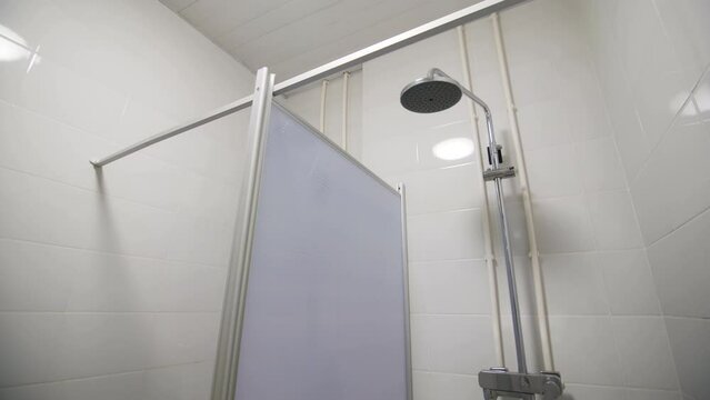 Clean public shower cabins with chrome heads in tiled room low angle shot. Body washing facilities and training equipment enclosure